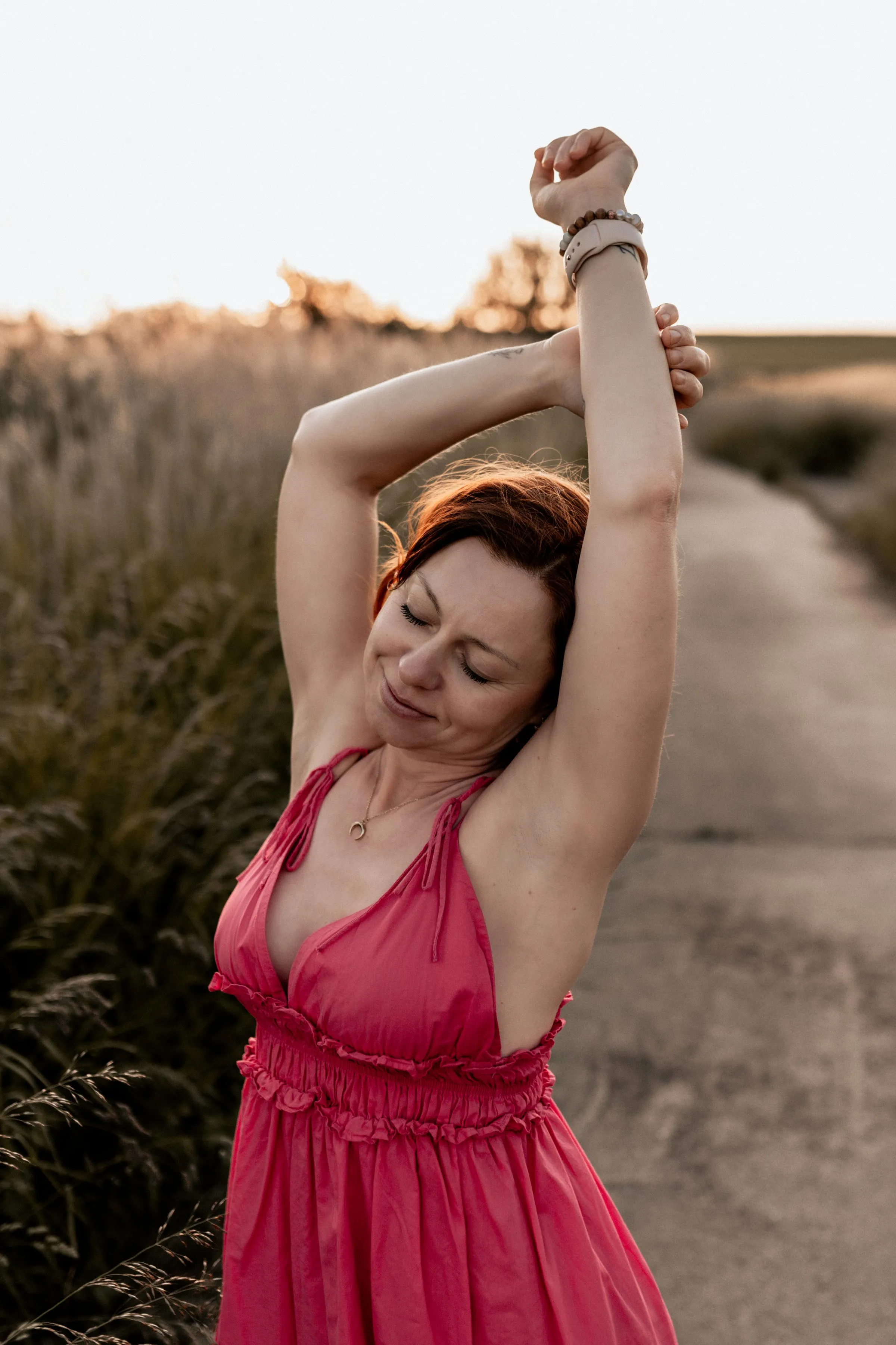 Lidia Baer im pinkfarbenen Sommerkleid, Arme erhoben, goldenes Abendlicht